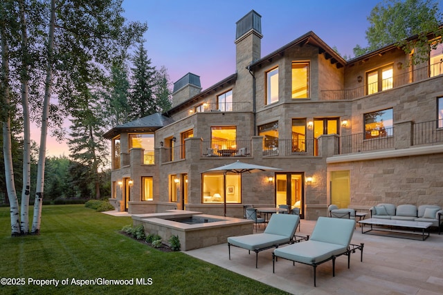 64 Pitkin Way, Aspen, CO 81611 - back of property at dusk featuring outdoor lounge area, a balcony, a yard, and a patio
