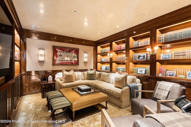 living area with built in shelves, crown molding, and wainscoting