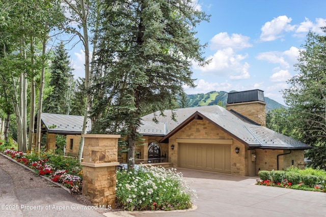 64 Pitkin Way, Aspen, CO 81611 - rustic home featuring a standing seam roof, stone siding, concrete driveway, metal roof, and a garage