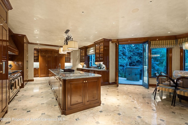 64 Pitkin Way, Aspen, CO 81611 - kitchen with dark stone countertops, ornamental molding, a sink, a center island with sink, and glass insert cabinets