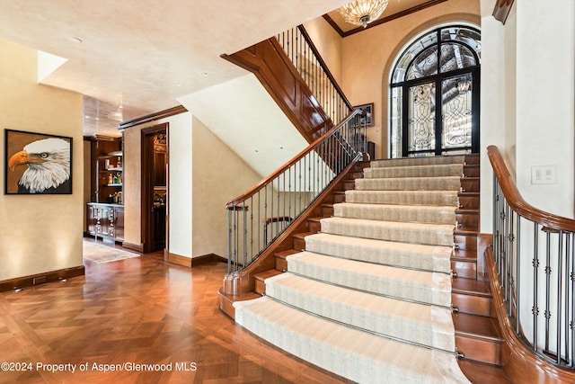 stairs with a towering ceiling, baseboards, and ornamental molding