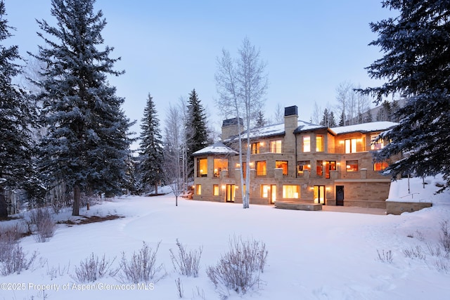 snow covered back of property with a chimney