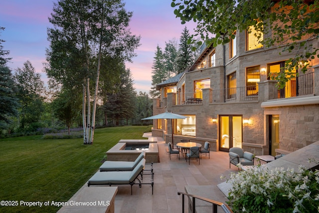 64 Pitkin Way, Aspen, CO 81611 - patio terrace at dusk featuring a lawn, a balcony, and an outdoor living space with a fire pit