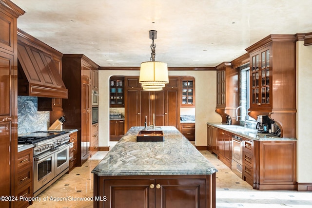 kitchen featuring hanging light fixtures, appliances with stainless steel finishes, brown cabinetry, and glass insert cabinets