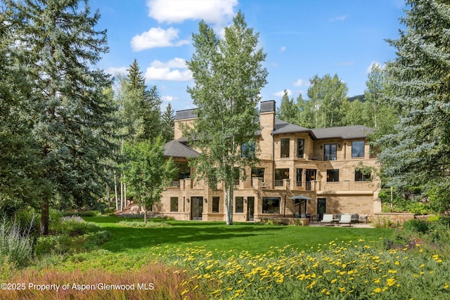 64 Pitkin Way, Aspen, CO 81611 - rear view of house featuring a lawn, a chimney, and a balcony