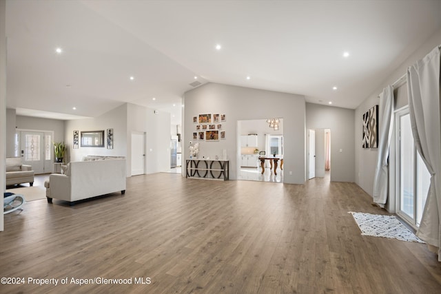 living room featuring a chandelier, high vaulted ceiling, and wood-type flooring