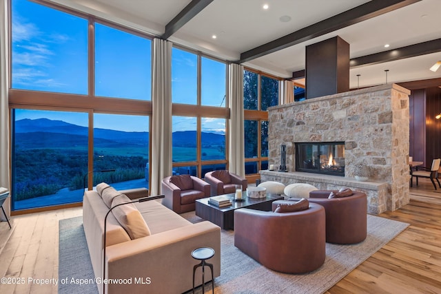 1000 Lazy O Rd, Snowmass, CO 81654 - living area featuring beamed ceiling, a stone fireplace, a mountain view, and wood finished floors