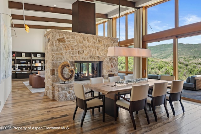 1000 Lazy O Rd, Snowmass, CO 81654 - dining area featuring a stone fireplace, a mountain view, a high ceiling, and wood finished floors