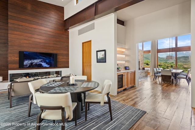 1000 Lazy O Rd, Snowmass, CO 81654 - dining room with wine cooler, wood walls, light wood-style flooring, and a towering ceiling