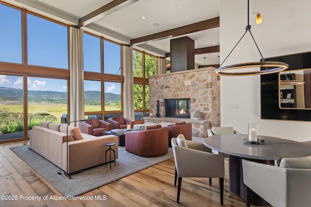 1000 Lazy O Rd, Snowmass, CO 81654 - living room with a high ceiling, wood-type flooring, a stone fireplace, beamed ceiling, and a mountain view