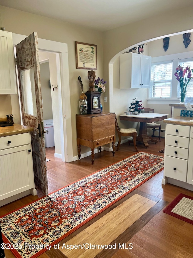 kitchen featuring light wood-type flooring, baseboards, white cabinets, and a baseboard radiator