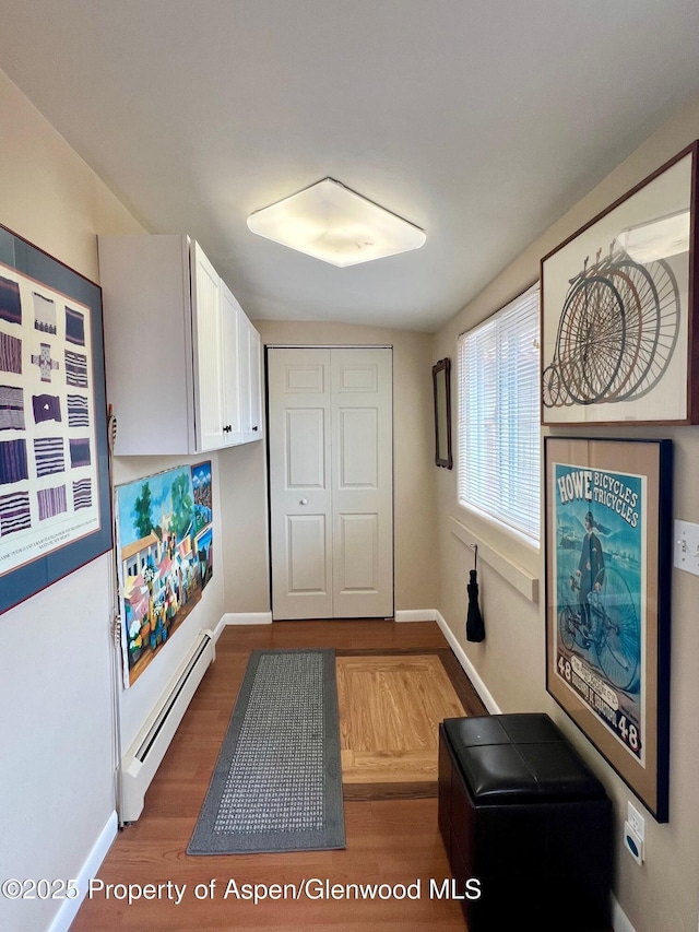 doorway to outside featuring a baseboard radiator, wood finished floors, and baseboards