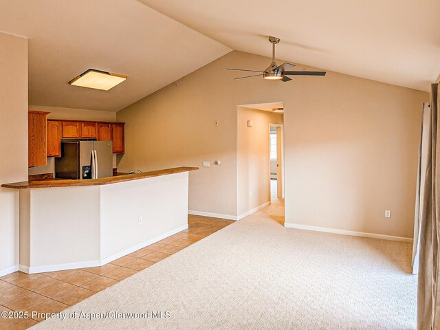 612 Riverview Dr Unit 808, New Castle, CO 81647 - kitchen with stainless steel refrigerator with ice dispenser, a ceiling fan, brown cabinets, light tile patterned flooring, and vaulted ceiling