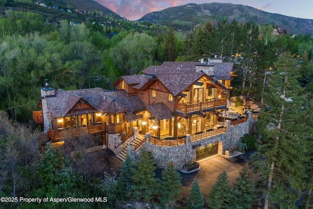 87 Magnifico Dr, Aspen, CO 81611 - view of front of property featuring a balcony, a mountain view, stone siding, a wooded view, and a chimney