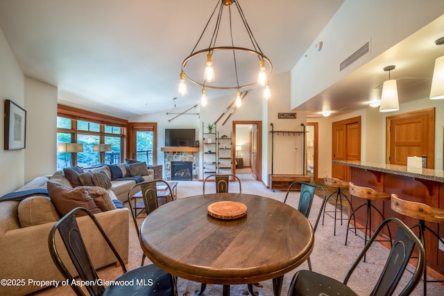 dining space with lofted ceiling, a fireplace, and visible vents