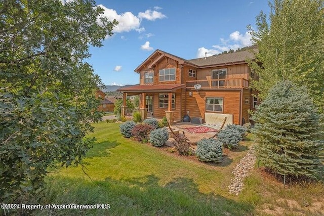 back of property featuring a yard, a patio, and a balcony