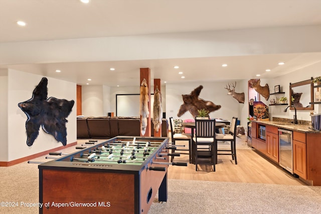 rec room with wine cooler, light hardwood / wood-style floors, and indoor wet bar