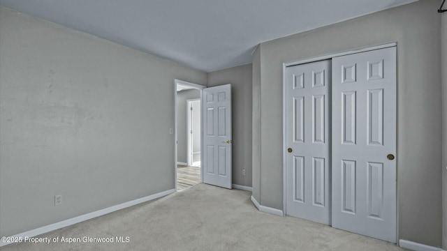 unfurnished bedroom with carpet, a closet, and baseboards