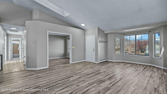 interior space with a baseboard heating unit, baseboards, wood finished floors, and lofted ceiling