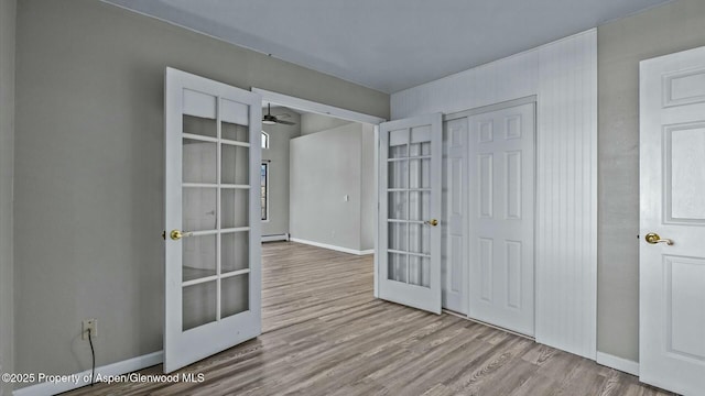 foyer featuring a baseboard radiator, french doors, baseboards, and wood finished floors