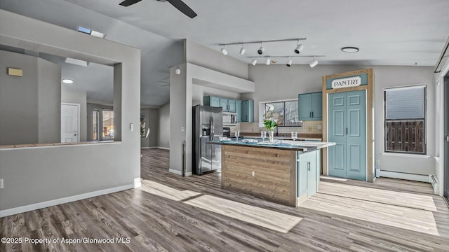 kitchen with ceiling fan, a baseboard radiator, appliances with stainless steel finishes, blue cabinets, and vaulted ceiling