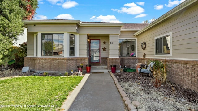 entrance to property with a lawn and brick siding