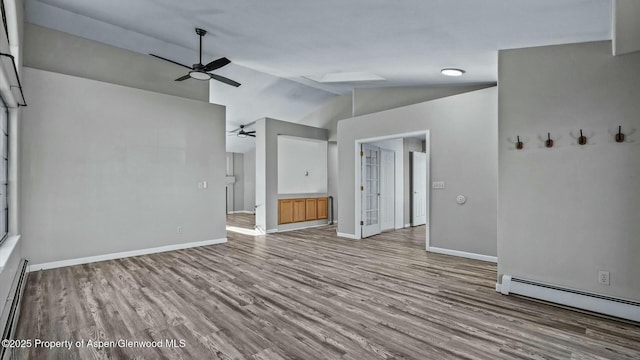 spare room with lofted ceiling, baseboard heating, a ceiling fan, wood finished floors, and baseboards