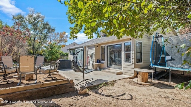 rear view of property featuring a trampoline, entry steps, a patio area, and fence