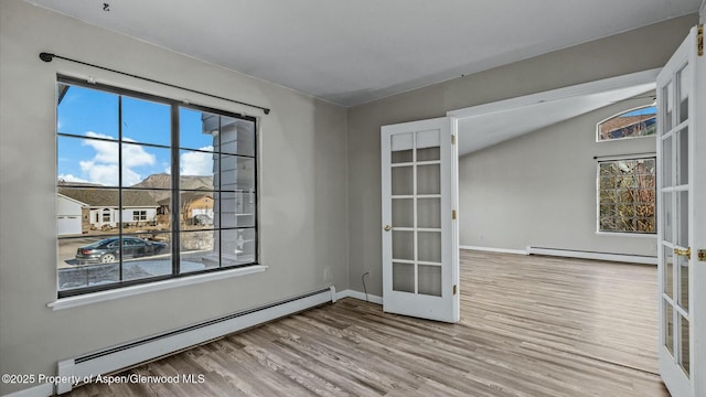 spare room with a baseboard heating unit, french doors, baseboards, and wood finished floors