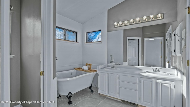 bathroom with double vanity, a freestanding tub, a sink, and tile patterned floors