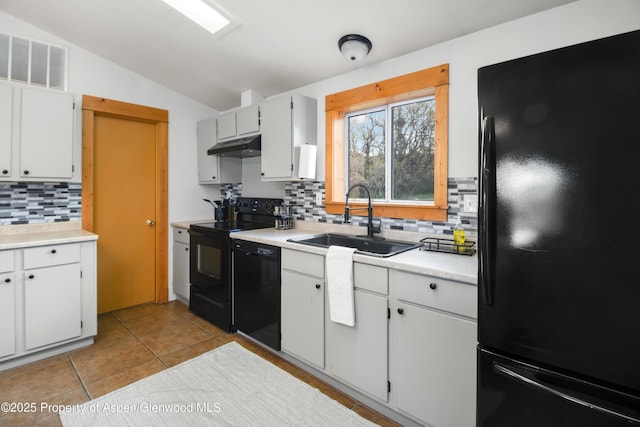 kitchen featuring black appliances, a sink, backsplash, light countertops, and vaulted ceiling