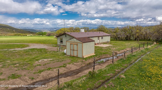 view of home's exterior with a storage unit, an outdoor structure, and a mountain view