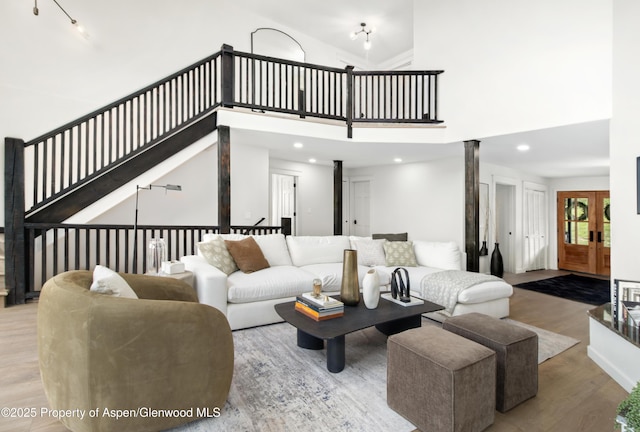 living room featuring wood finished floors, recessed lighting, a towering ceiling, and ornate columns