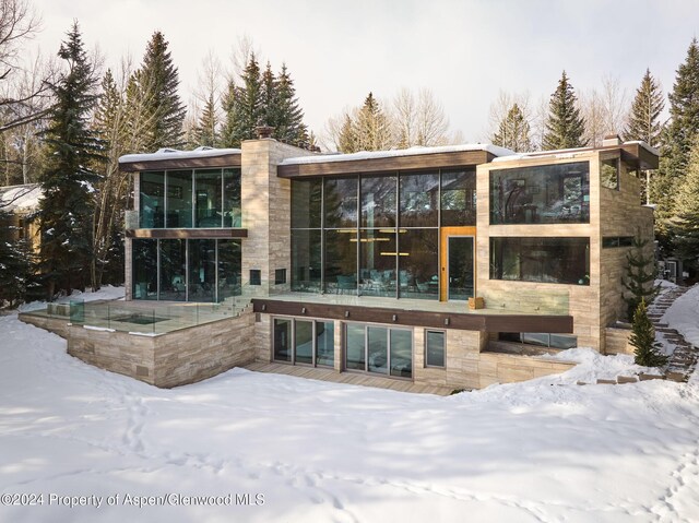 snow covered house featuring a sunroom