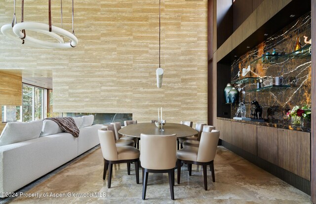 dining room featuring a high ceiling and wood walls