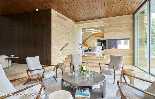 sitting room with wood walls, a fireplace, and wooden ceiling