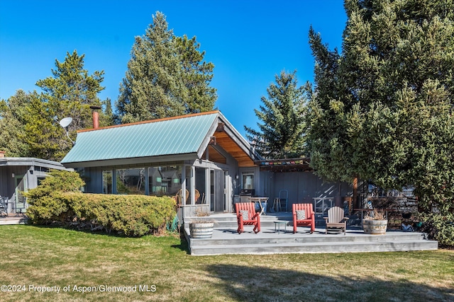 rear view of house featuring a yard and a sunroom