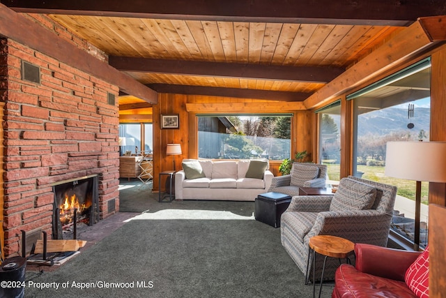 living room featuring beam ceiling, wood walls, wood ceiling, dark carpet, and a fireplace