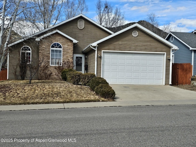 single story home featuring a garage, concrete driveway, and stone siding