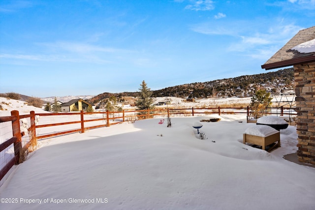 snowy yard featuring fence and a mountain view