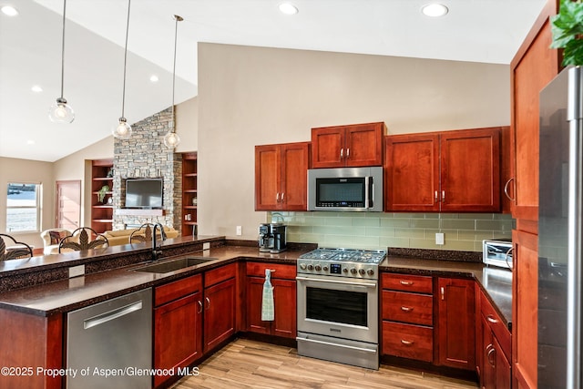 kitchen with appliances with stainless steel finishes, dark countertops, a sink, and a peninsula