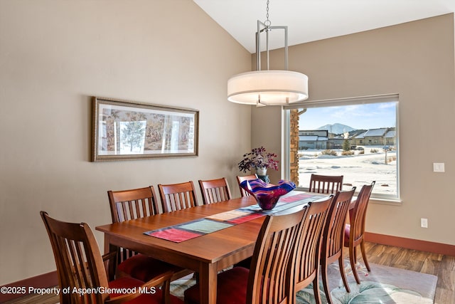 dining space featuring lofted ceiling, baseboards, and wood finished floors