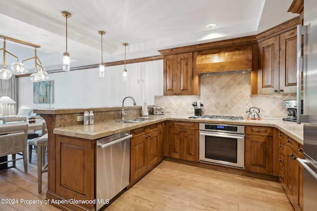 kitchen featuring kitchen peninsula, appliances with stainless steel finishes, decorative light fixtures, custom range hood, and sink