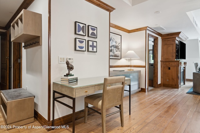 dining area with crown molding, built in desk, and light hardwood / wood-style floors