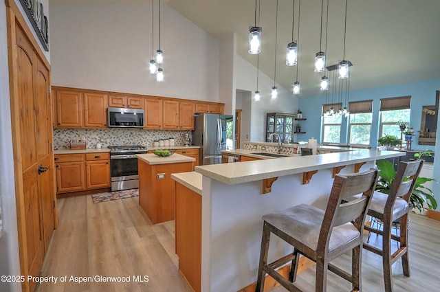 369 N Meadow Dr, Rifle, CO 81650 - kitchen with appliances with stainless steel finishes, a spacious island, light wood-style floors, light countertops, and high vaulted ceiling
