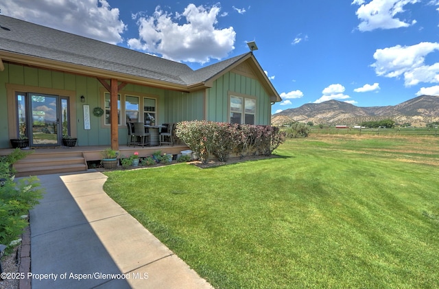 369 N Meadow Dr, Rifle, CO 81650 - view of side of home with covered porch, board and batten siding, a mountain view, a lawn, and a shingled roof