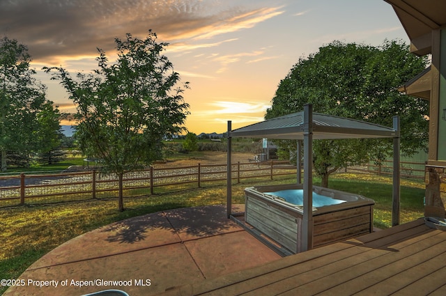 369 N Meadow Dr, Rifle, CO 81650 - deck at dusk featuring a hot tub, a fenced backyard, and a patio