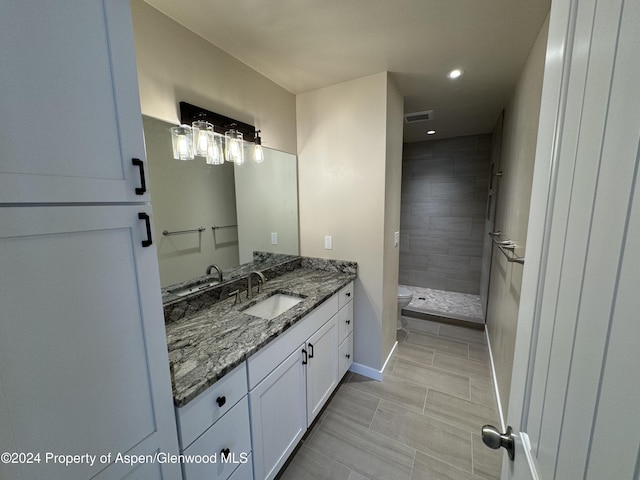 bathroom with vanity, toilet, and a tile shower