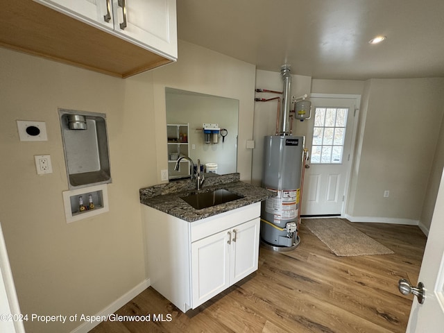 kitchen with water heater, sink, white cabinets, dark stone counters, and light hardwood / wood-style floors