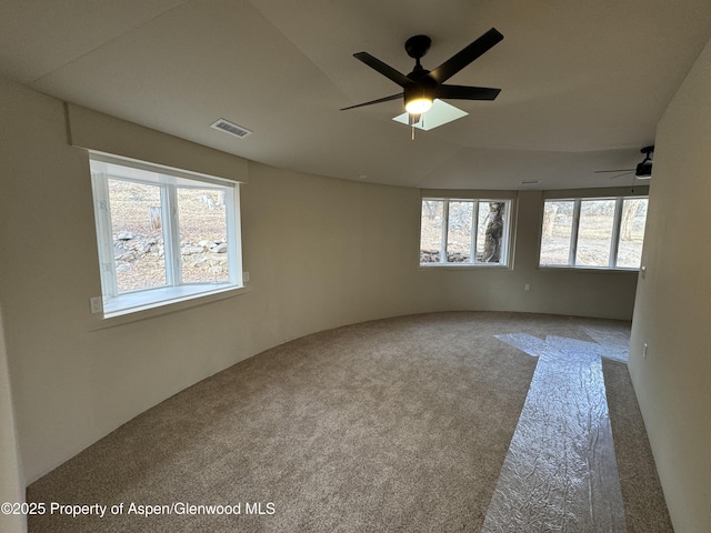 empty room featuring ceiling fan, carpet floors, and a wealth of natural light